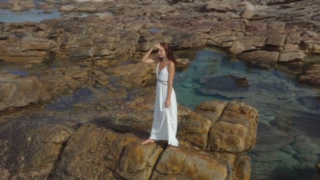 Aerial Drone View of Bride Woman in an White Dress on a Rocky Cliff