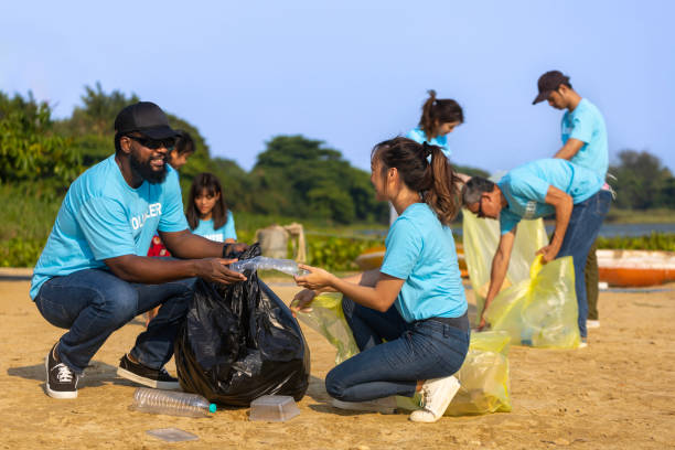 une équipe de jeunes et d’un groupe de travailleurs bénévoles de la diversité profite d’un travail social caritatif à l’extérieur dans le cadre d’un projet de nettoyage des ordures et du tri des déchets à la plage de la rivière - bag garbage bag plastic black photos et images de collection