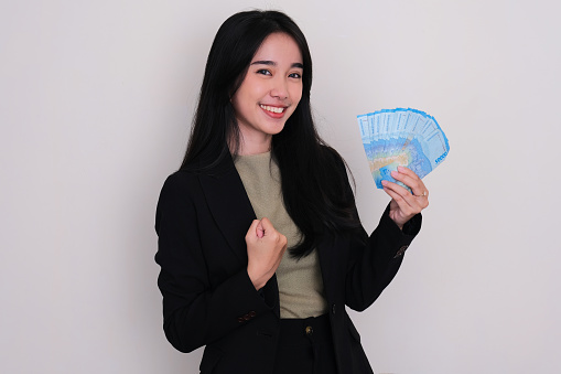 Asian young woman smiling and clenched fist while holding money