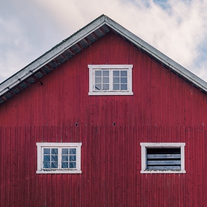 A red wooden rural house with white windows on a cloudy day
