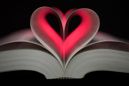 Love heart shape from pages folded with red light shining through