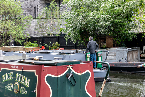 London. UK- 05.04.2023. A man sailing a barge on Regent's Canal in the capital.