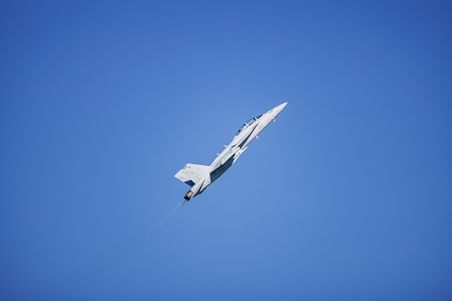 OshKosh, United States – July 29, 2022: A US Navy F-18 fighter jet in flight against a clear blue sky at Wittman Regional Airport