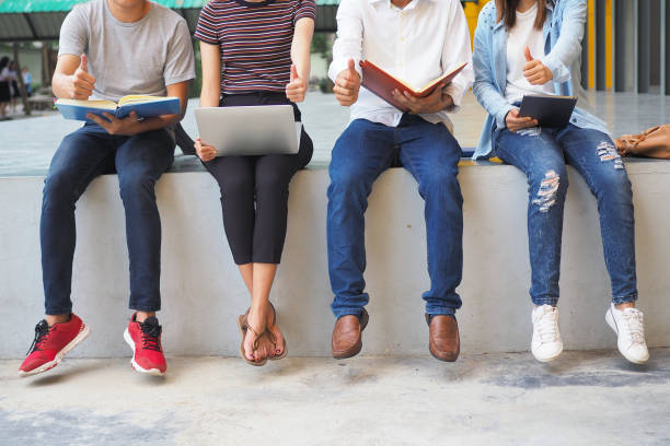 istock Young people sit in lined rows reading books using laptops and smartphones. Group together for entertainment and knowledge. 1488085130