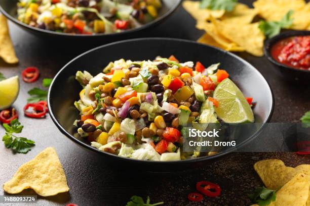 Mexican Style Salad Of Black Beans Lentils Corn Tomato And Lettuce With A Salsa And Tortilla Chips Stock Photo - Download Image Now