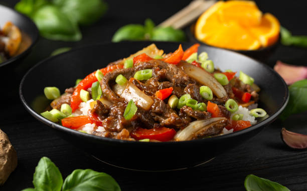 frite a carne de laranja crocante com pimentão, cebola e arroz. comida asiática - beef rice orange stir fried - fotografias e filmes do acervo