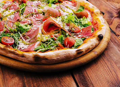 Pizza with prosciutto meat, cherry tomatoes, arugula and parmesan cheese