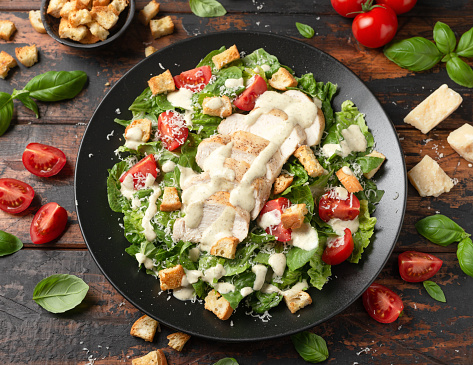 A delicious chicken caesar salad with parmesan cheese, tomatoes, croutons and dressing.