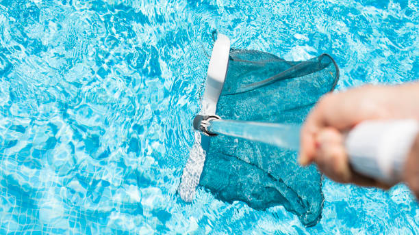 staff cleaning the pool with sweeper or cleaning leaves before bathing. Removing leaves from the pool with pool netting. Cleaning with Skimmer Nets to remove Dirt from the Pool