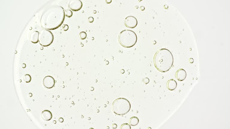 Transparent cosmetic gel fluid with molecule bubbles oil distribution on a white background. Macro Shot of Natural Organic Cosmetics, Medicine. Production Close-up. Slow Motion