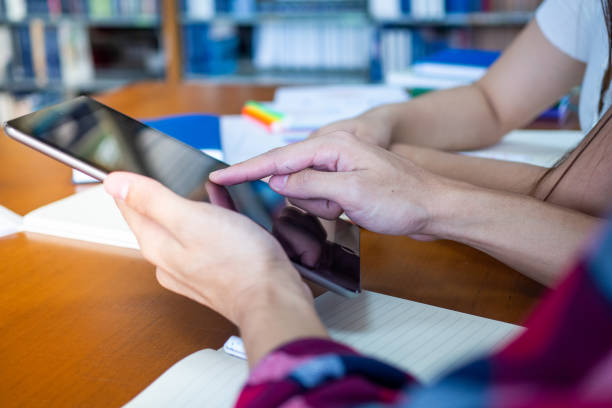istock Students use the tablet to find educational information in the library. Learning and reading online 1488097387