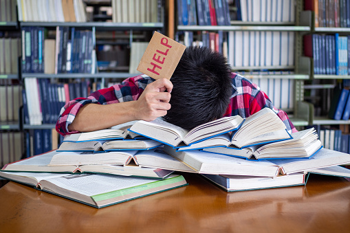 Asian male students are tired and stressed with reading a lot to prepare for the exam.