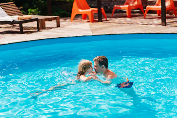 istock Dad and daughter have fun and swim with inflatable circle in the pool. 1488097656