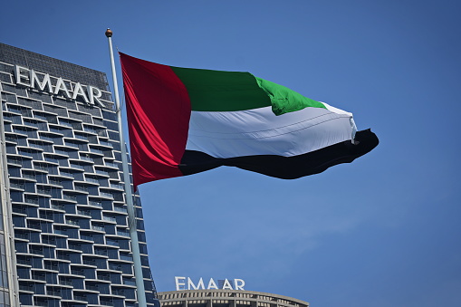 A flag of the United Arab Emirates flying against the clear, calm sky. UAE celebrates its national holiday on 2 December each year.