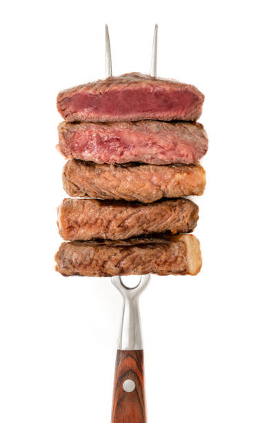 Slice of beef steak on meat fork isolated on white background.