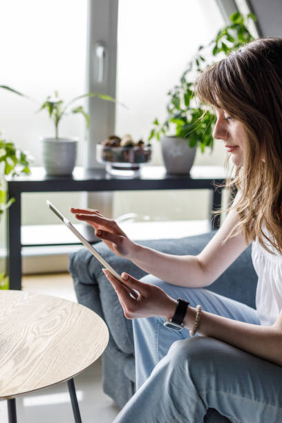 istock Young woman sitting on the sofa, relaxing and using digital tablet 1488099794