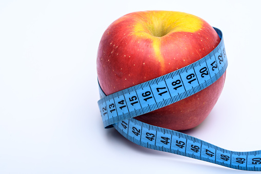 An apple on a white background with a tailor's measure.  symbol of diet, slimming, losing weight, nice figure