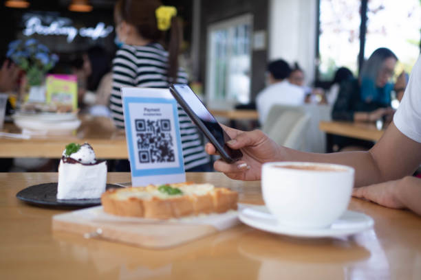 Women's hands are using  the phone to scan the qr code to select food menu. Scan to get discounts or pay for food. The concept of using a phone to transfer money or paying money online without cash.