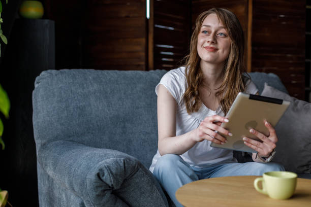istock Young woman relaxing on the sofa, using digital tablet and contemplating 1488102700