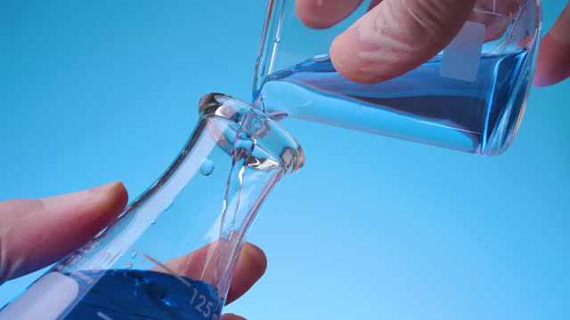 Pouring blue liquid solution in laboratory flask