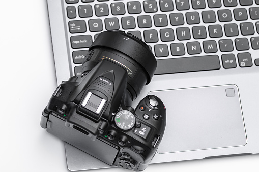 DSLR camera lying on a laptop keyboard on a white background