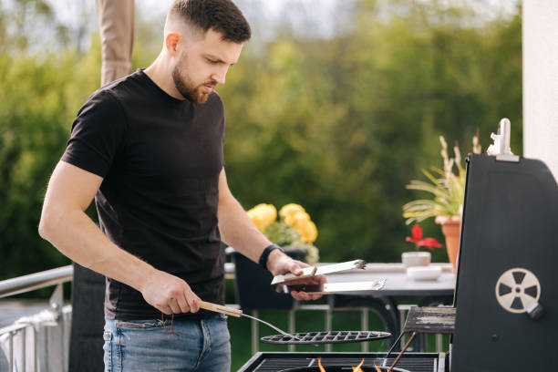 istock Side view of handsome man preparing bonfire to make steak in barbecue 1488111583