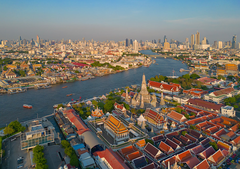 Aerial top view of Temple of Dawn or Wat Arun statue and Chao Phraya River, Bangkok, Thailand in Rattanakosin Island in architecture, Urban old town city, skyline at sunset.