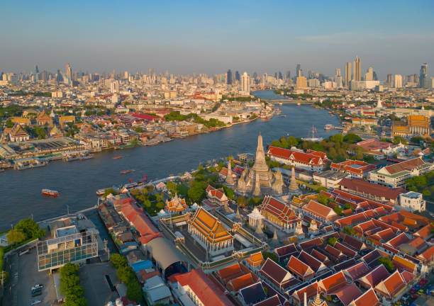 Aerial top view of Temple of Dawn or Wat Arun statue and Chao Phraya River, Bangkok, Thailand in Rattanakosin Island in architecture, Urban old town city, skyline at sunset. stock photo
