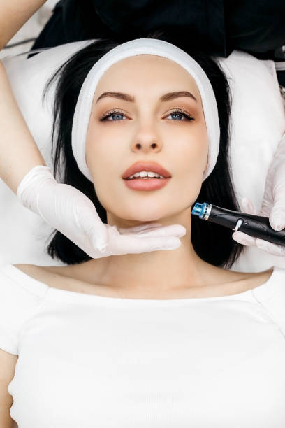 istock Professional qualified beautician standing next to client during Hydradermabrasian procedure. Pleasant beauty procedure. Joyful positive woman smiling while enjoying the beauty procedure 1488115617