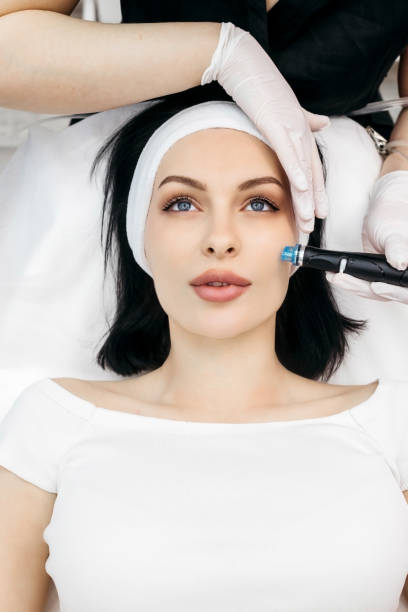 istock Professional qualified beautician standing next to client during Hydradermabrasian procedure. Pleasant beauty procedure. Joyful positive woman smiling while enjoying the beauty procedure 1488115637