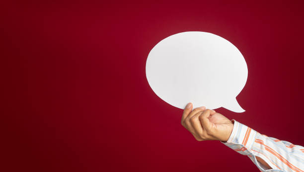 istock Hand holding an empty white speech bubble over on a red background with copy space for text 1488116995