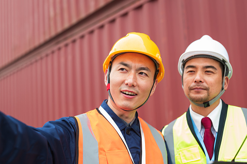 Two Asian container yard managers work in the yard management, container freight concept, and transportation industry staff