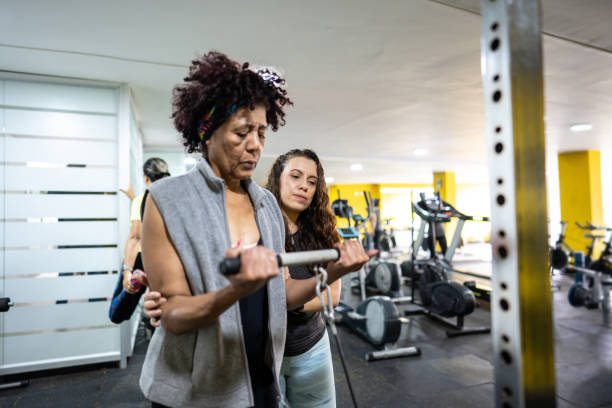 Female fitness instructor helping senior woman in the gym