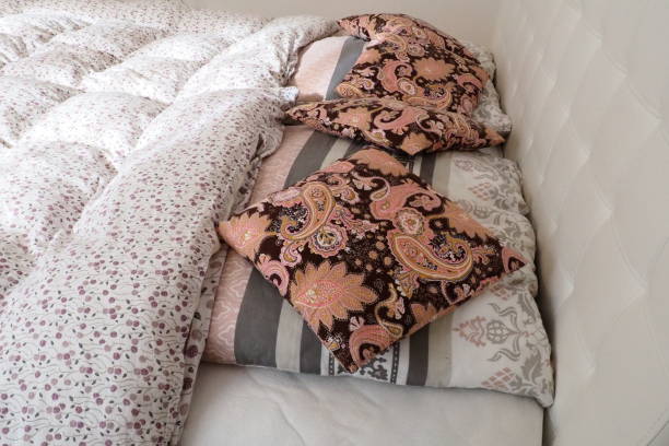 istock Pink decorative pillows on the bed linen. Double bridal bed with pillows and thick feather duvet. Bedroom design. Soft white headboard. Interior with furniture and bedding. 1488124627