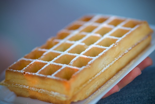 A closeup of a fresh waffle covered with sugar powder