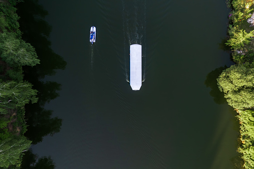 drone view of boats with motors sailing in parallel, trees along the banks. landscape on a summer evening on the river