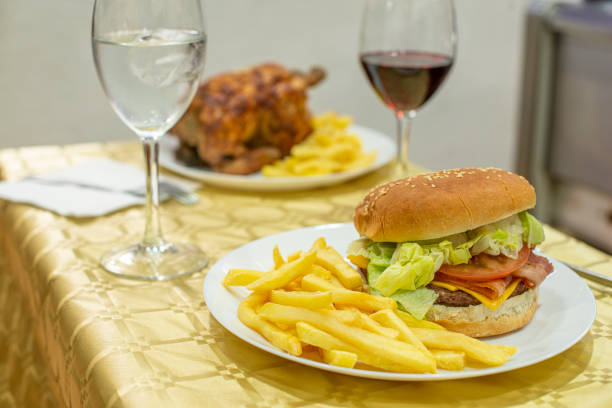 Classic burger on a summer menu with roast chicken and fries. Beef burger with cheddar cheese, fried bacon, tomato and lettuce, ketchup and mustard