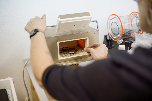 the jeweler puts the ring into the baking oven