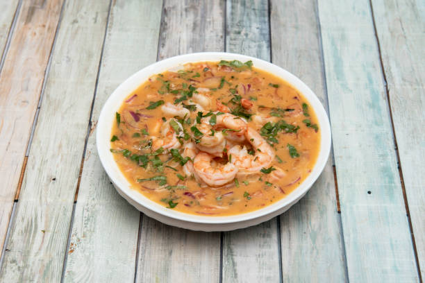 Shrimp ceviche with a lot of product and a lot of juice with parsley and red onion Shrimp ceviche with a lot of product and a lot of juice with parsley and red onion on wooden table raw croaker fish stock pictures, royalty-free photos & images
