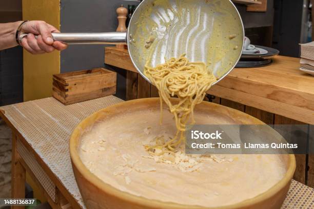 https://media.istockphoto.com/id/1488136837/photo/mans-hand-pouring-fat-spaghetti-from-a-frying-pan-over-half-grana-padano-cheese-in-an-italian.jpg?s=612x612&w=is&k=20&c=0kJ1TkJdcnWYXHR9uLXBRpsCL2jPrPCE6oTwpo-MuzA=