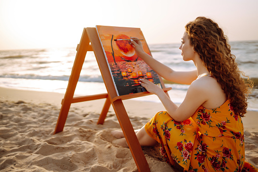 Young woman drawing the picture at the beach.