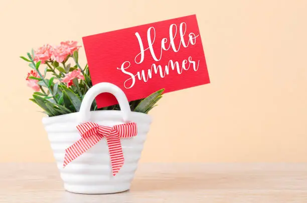 Photo of The Hello summer on red card with flowers bouquet in vase.