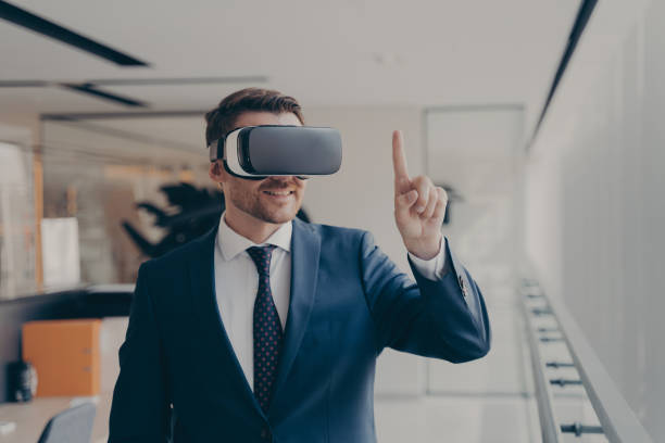 istock Smiling bearded office employee in suit wearing in VR glasses working in augmented reality in office 1488143083