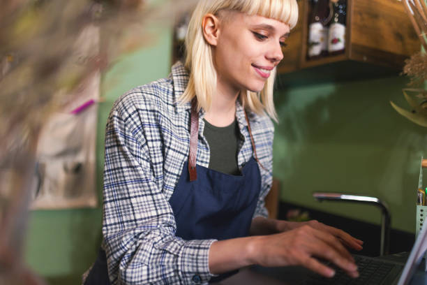 istock Cheerful botanist uses a laptop while working in a flower shop 1488143501