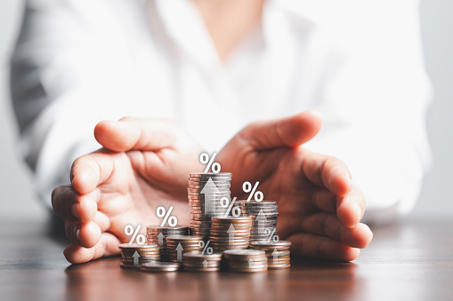 Businesswoman hand giving heap of coins money with up arrow and percentage symbol of Interest rate financial and mortgage rates. Icon percentage symbol and arrow pointing up.