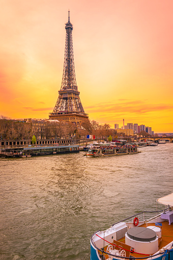 The Eiffel Tower and the arching Pont d'Iéna Bridge at sunrise over the moored houseboat in the Seine River in Paris, France