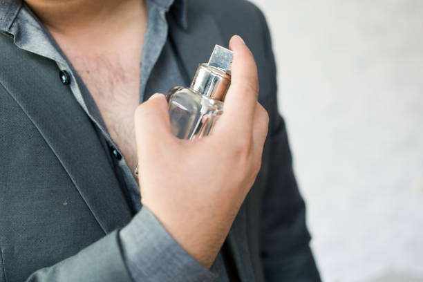 istock Handsome man applying perfume on neck, close up 1488148396
