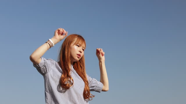 Young female influencer dancing under the sky for live streaming