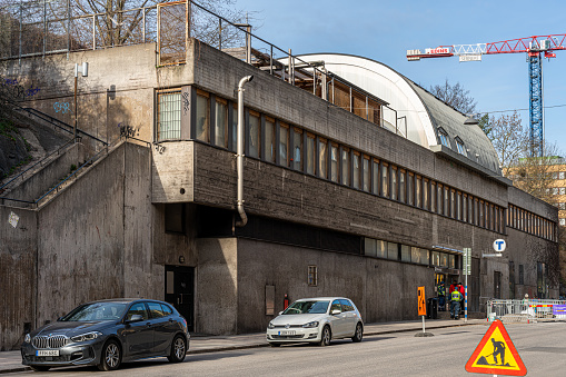 Stockholm, Sweden - April 16, 2022: Outdoor street view of old concrete subway station building entrance with incidental people in Stockholm Sweden April 16, 2022.