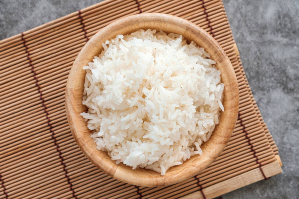 Thai Jasmine Rice in Wooden Bowl. Top Table View Of Thai Jasmine Rice in Wooden Bowl, staple food of Thailand and Asia, providing energy in every meal. jasmine rice stock pictures, royalty-free photos & images